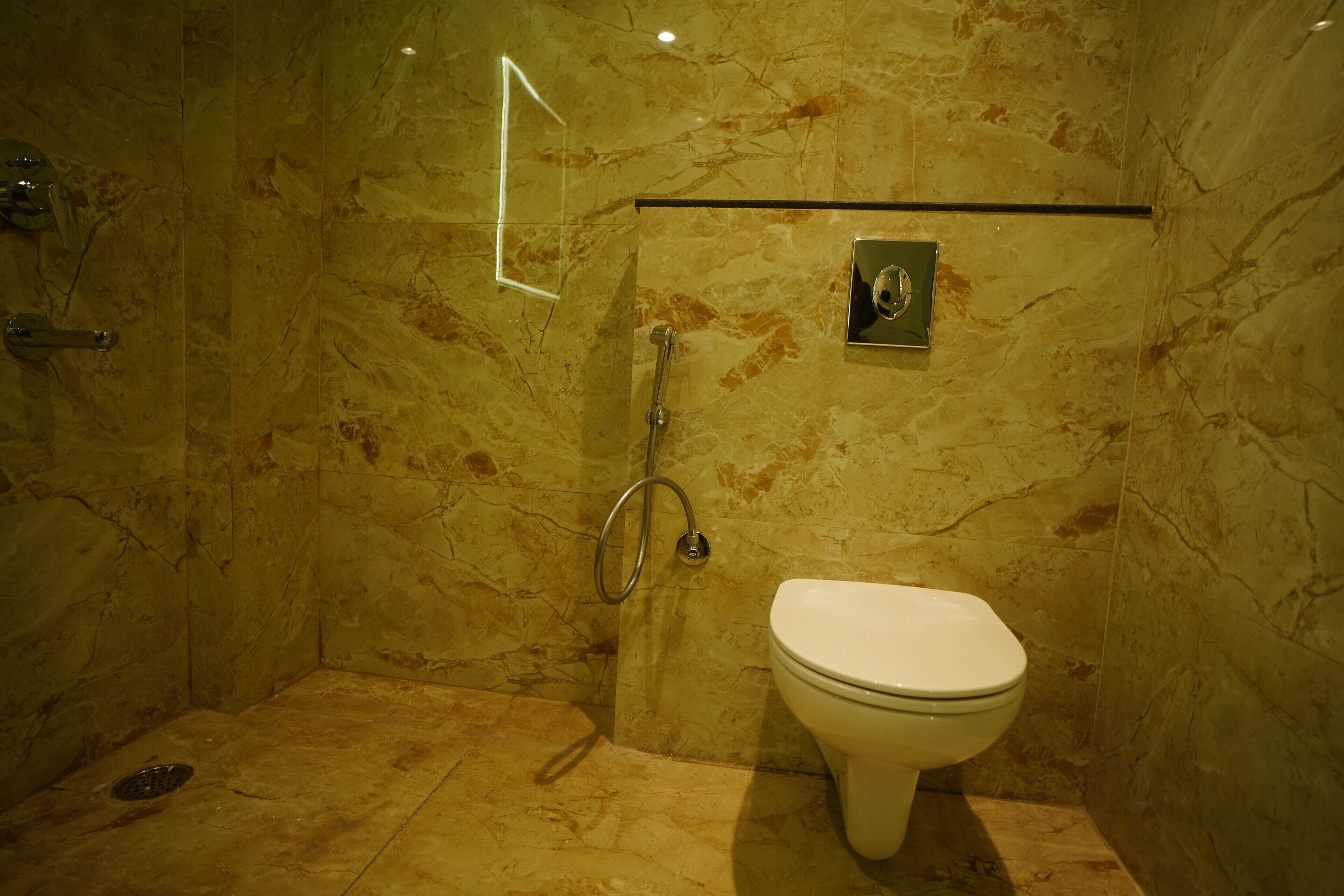 A bathroom with a marble floor, a toilet, and a shower area with a glass door.