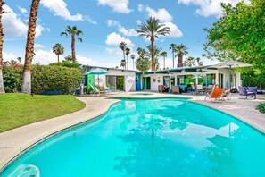 Un espace piscine avec des chaises longues et un bâtiment doté d’une terrasse donnant sur la piscine.