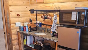 A compact kitchen with wooden walls, a stainless steel refrigerator, a microwave, and a hanging light fixture. - Cabin with Private HOT TUB!!!  8 minutes to Ark Encounter!!! (Dry Ridge)