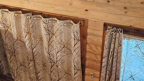 A room with wooden walls, a ceiling fan, a painting of bison, and curtains with tree patterns. - Cabin with Private HOT TUB!!!  8 minutes to Ark Encounter!!! (Dry Ridge)