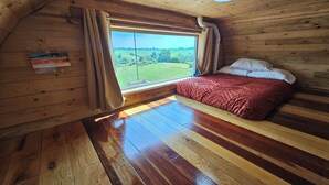 A wooden cabin room with a bed, a window with curtains, and a view of a green landscape. - Cabin with Private HOT TUB!!!  8 minutes to Ark Encounter!!! (Dry Ridge)