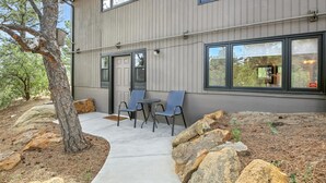 A modern two-story building with a gray exterior, large windows, and a patio area with outdoor seating.