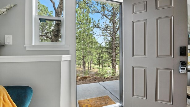 A door leading to a covered outdoor area with a view of trees and a clear sky.