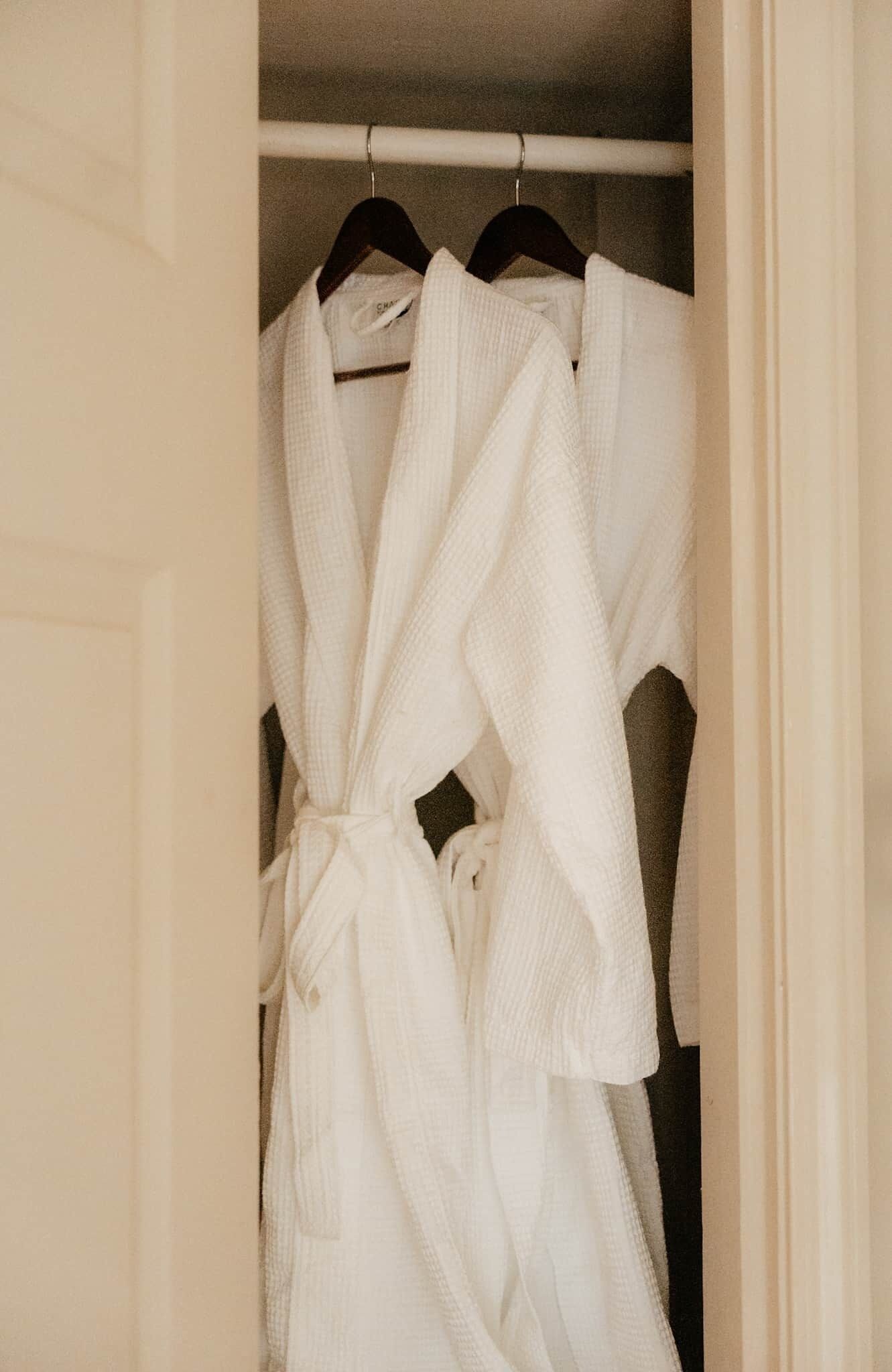 A white robe hanging on a closet rod.