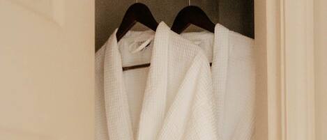 A white robe hanging on a closet rod.