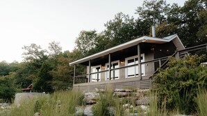 Ein modernes Haus mit überdachter Veranda, umgeben von natürlicher Vegetation und Felsen.