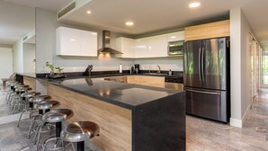 A modern kitchen with a central island, stainless steel appliances, and a long bar seating area.