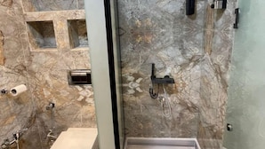 Une salle de bain moderne avec un sol en marbre, une douche en verre, des toilettes et un lavabo.