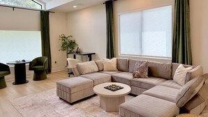 Una sala de estar moderna con un sofá seccional, una mesita redonda y un comedor con una pequeña mesa y sillas.