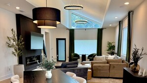 Una sala de estar moderna con comedor, chimenea y ventanas amplias con cortinas.