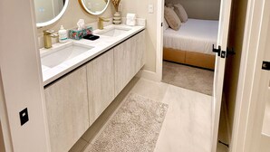 Un baño moderno con un espejo grande, dos lavamanos y una ducha a ras de suelo.