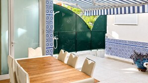 A dining area with a wooden table and white chairs, a green door, and a patterned wall.