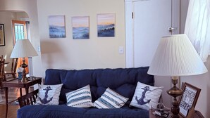 A living room with a dark blue sofa, a patterned rug, and a lamp on a wooden side table. - Charming 2-bedroom house with a river view in wonderful Madison (Madison)