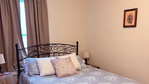 A neatly made bed with a patterned bedspread, a bedside table with a lamp, and a framed picture on the wall. - Charming 2-bedroom house with a river view in wonderful Madison (Madison)