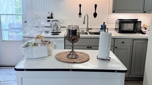 A modern kitchen with white cabinetry, a central island, and a microwave. - Charming 2-bedroom house with a river view in wonderful Madison (Madison)