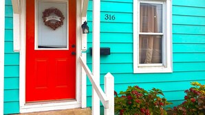 A turquoise house with a red door, a number '316' on the side, and a small window. - Charming 2-bedroom house with a river view in wonderful Madison (Madison)