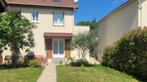 A two-story house with a front door, a small porch, and a satellite dish. - Charming 35 m2 apartment with terrace and garden (Domont)