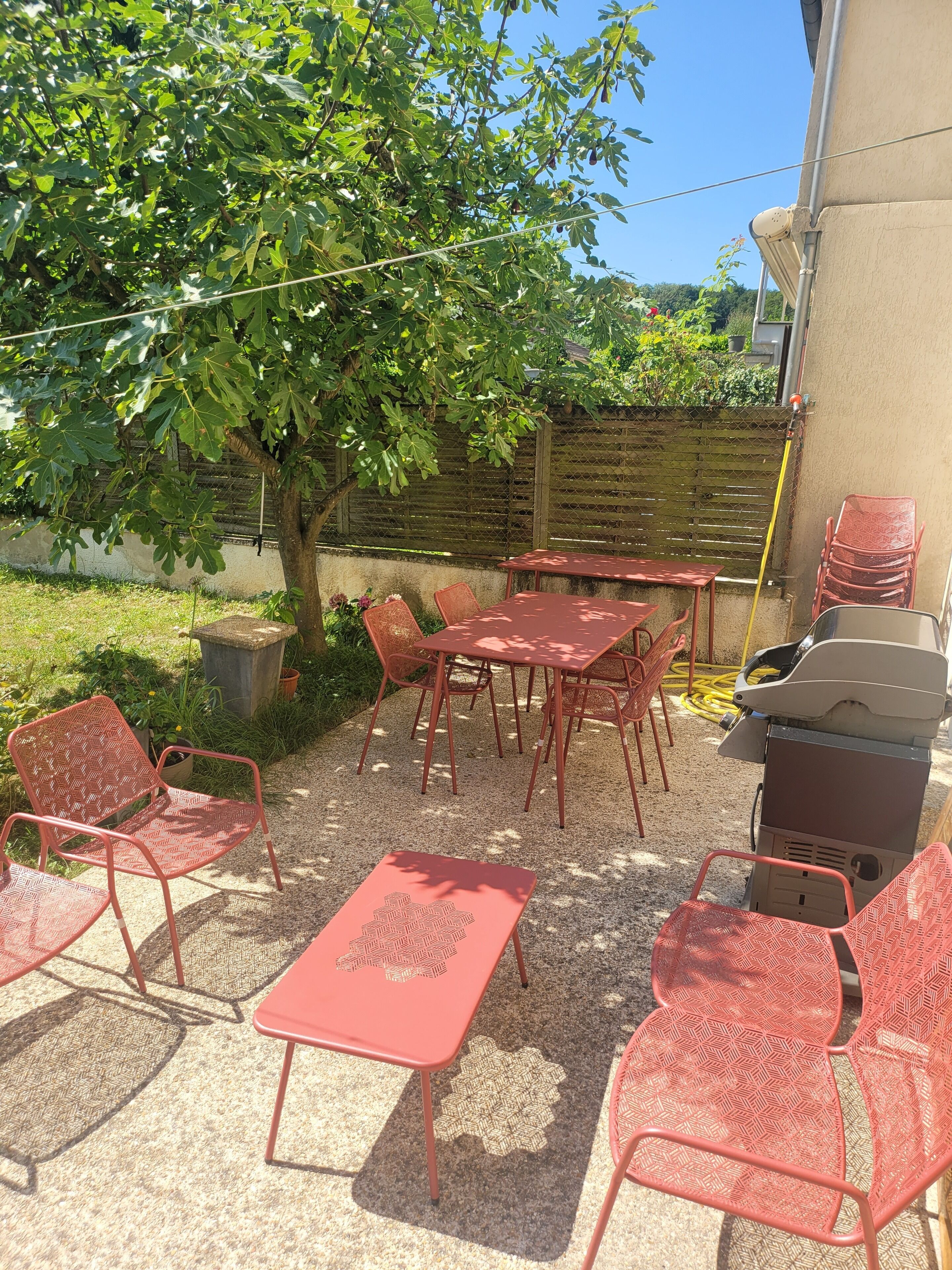 Une terrasse extérieure avec des meubles en métal rouge, une table et des chaises.