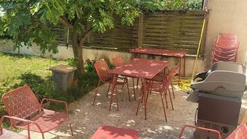 An outdoor patio with red metal furniture, a table, and chairs.