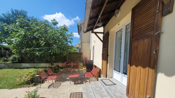 A patio with outdoor seating, a small grill, and a tiled entrance. - Charming 35 m2 apartment with terrace and garden (Domont)