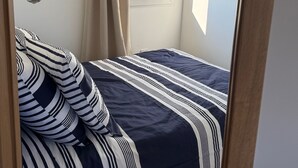 A bedroom with a bed, a window, and a hanging light fixture.