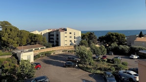 A residential area with a parking lot, buildings, and a view of the sea.