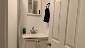 Une salle de bain avec des meubles blancs, un lavabo, un miroir et une serviette accrochée au mur.