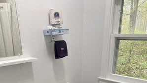 A bathroom with a white sink, toilet, and a window with a view of trees.