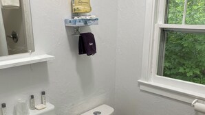 A bathroom with a white sink, toilet, and a window with a view of greenery.
