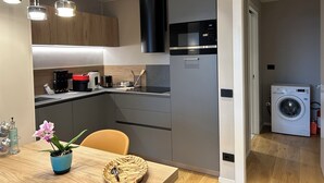 A modern kitchen with a built-in microwave, a refrigerator, and a washing machine in the adjacent room. - Exclusive flat on Lake Como with panoramic views (Como)