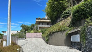 A paved pathway leading to a building with a stone wall and greenery on one side. - Exclusive flat on Lake Como with panoramic views (Como)