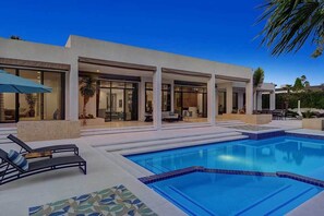 Una casa moderna con piscina, mobiliario exterior y un espacio de patio.