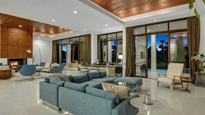 Una sala de estar moderna con un sofá seccional, una chimenea y ventanas amplias que ofrecen vistas al exterior.