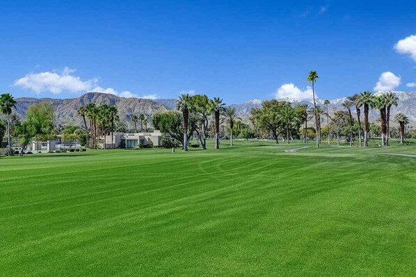 A well-maintained golf course with a clear view of mountains in the background.