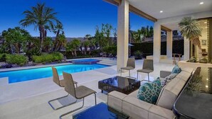 Un espacio moderno al aire libre con piscina, mobiliario y vistas del paisaje circundante.