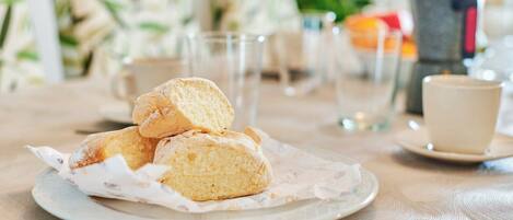 A plate with three biscuits on a table with a cup and saucer in the background.