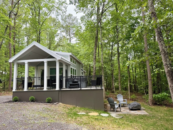 A cabin with a porch, a covered outdoor seating area, and a stone pathway leading to a chair and table.