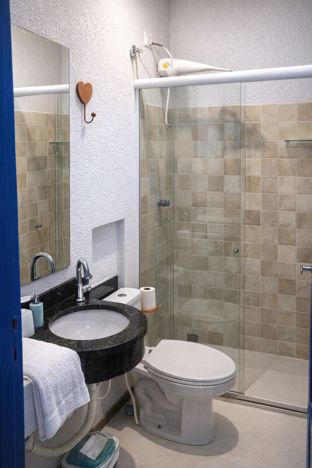 Um banheiro moderno com box de vidro, vaso sanitário branco e pia de granito.