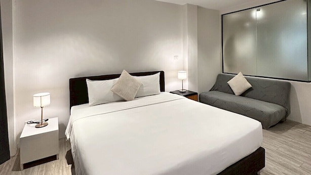 Un hotel moderno con una cama grande, un sofá y un espejo grande en la pared.