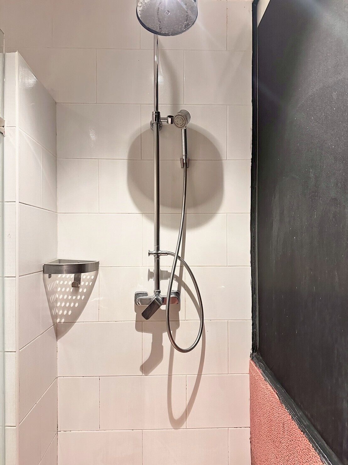 A shower with a handheld showerhead and a handheld shower attachment.