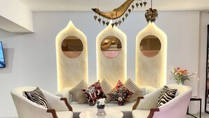 Una sala de estar moderna con un sofá, dos sillones, una mesa de centro y apliques decorativos en la pared.