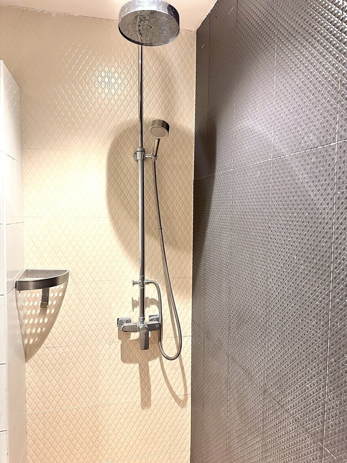 A shower with a handheld showerhead and a handheld shower attachment.