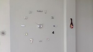 A wall clock with numbers and hands, a small table with candles, and a speaker. - Delightful 4bedroom house in Plateritos,Canoas d Punta Sal,Contralmirante Villar (Tumbes)