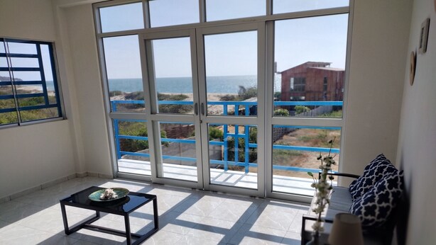 A balcony with a view of the beach and a building in the distance. - Delightful 4bedroom house in Plateritos,Canoas d Punta Sal,Contralmirante Villar (Tumbes)