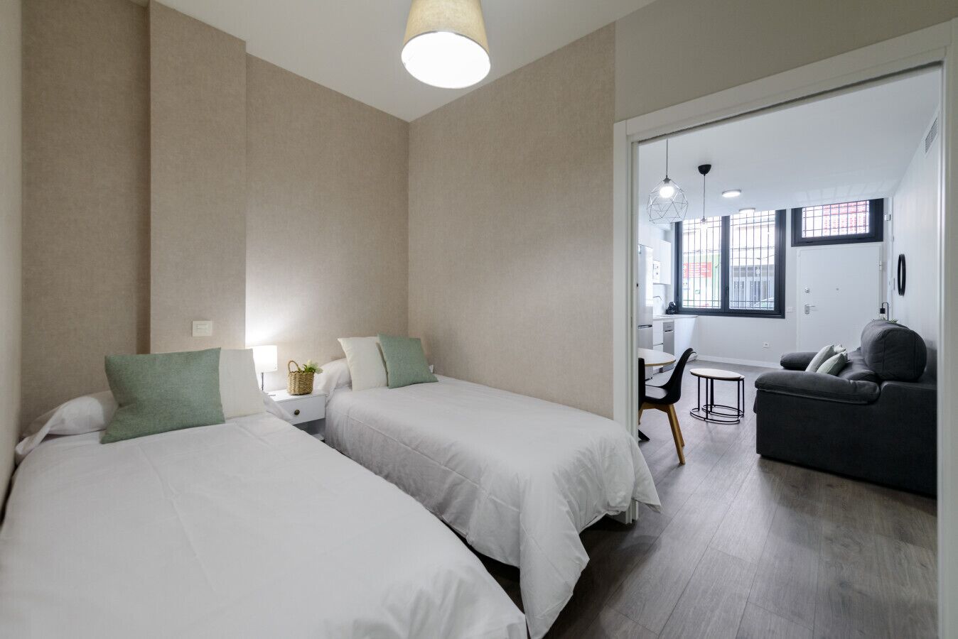 Habitación de hotel con dos camas, un sofá, una mesita y vistas a la cocina y al comedor.