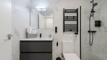 Un baño moderno con pared de mármol, toallero negro, inodoro y ducha.