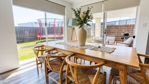 A dining area with a wooden table, wicker chairs, and a vase with flowers.