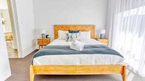 A hotel room with a wooden bed, white bedding, a blue and white patterned throw, and two bedside tables with lamps.