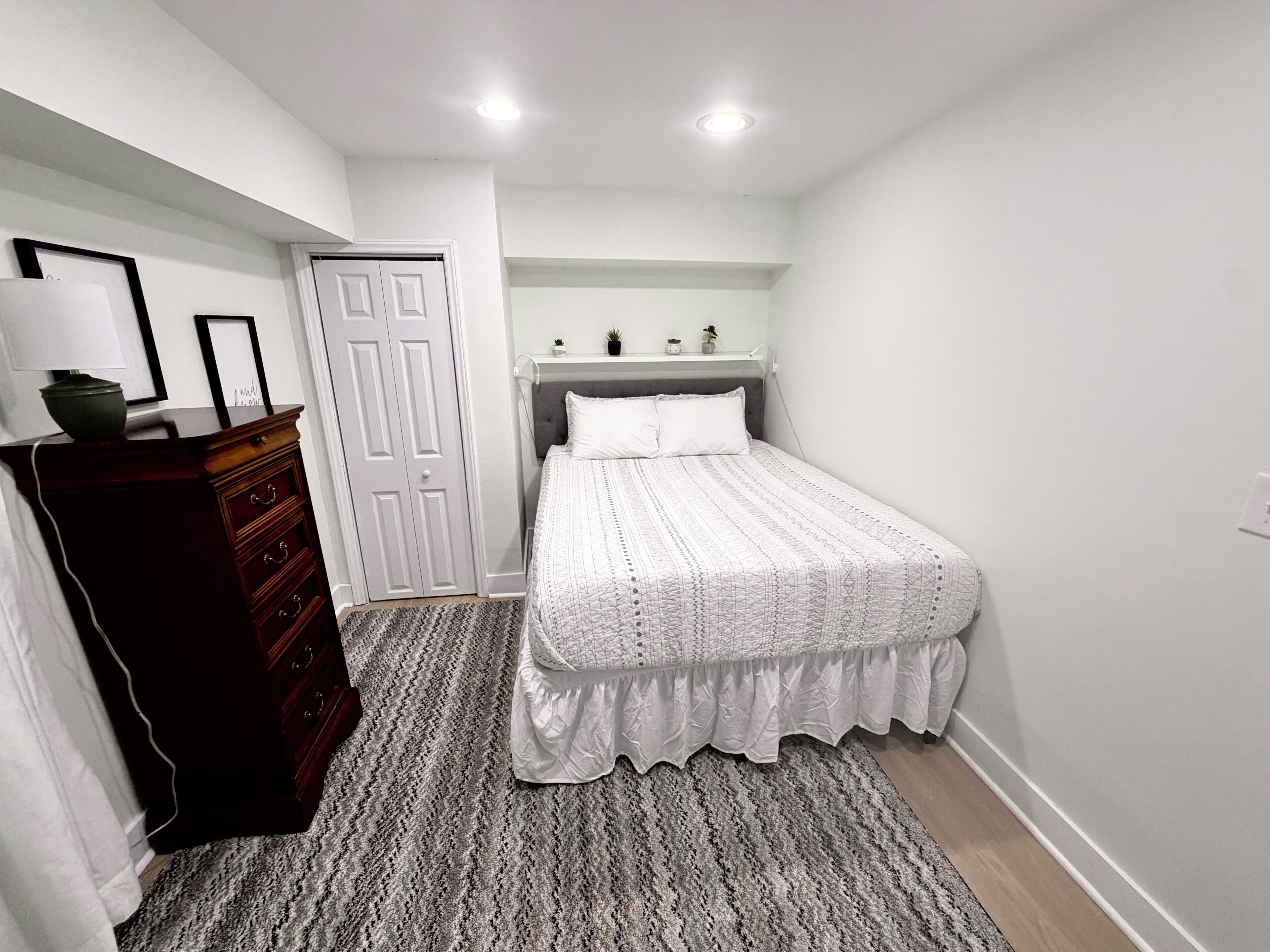 A bedroom with a bed, dresser, and a door.
