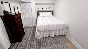A bedroom with a bed, dresser, and a door.